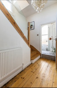 a small hallway with a wooden floor and stairs