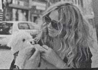 a black and white photo of a woman holding a dog