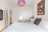 a bedroom with a white bed and a pink lamp