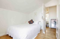 a bedroom with wooden floors and a white bed