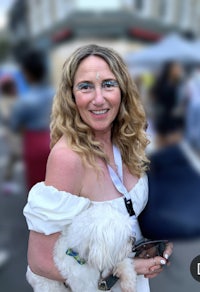 a woman holding a white dog in front of a crowd