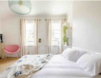 a bedroom with a white bed and a pink chair