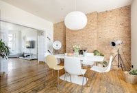 a dining room with a brick wall and white chairs