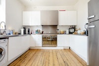 a white kitchen with wooden floors and a washing machine