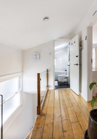 a white bathroom with wooden floors and a potted plant