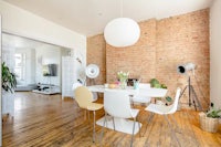 a white dining table and chairs in a room with brick walls